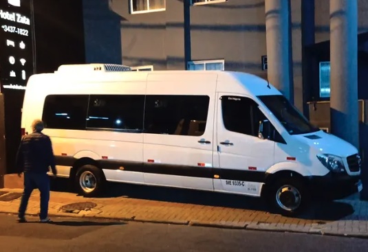 Van da Bento & Bento Turismo parada a noite em frente a um hotel, durante um transfer.